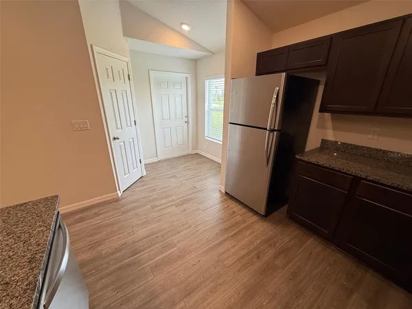 a view of a kitchen with wooden floor and refrigerator
