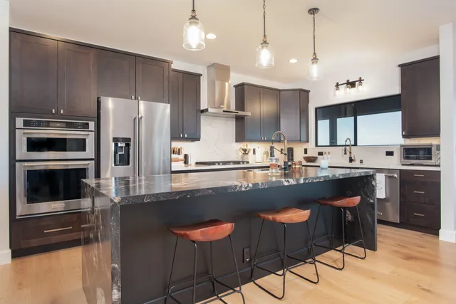 a kitchen with stainless steel appliances a sink a stove a refrigerator cabinets and a counter top space