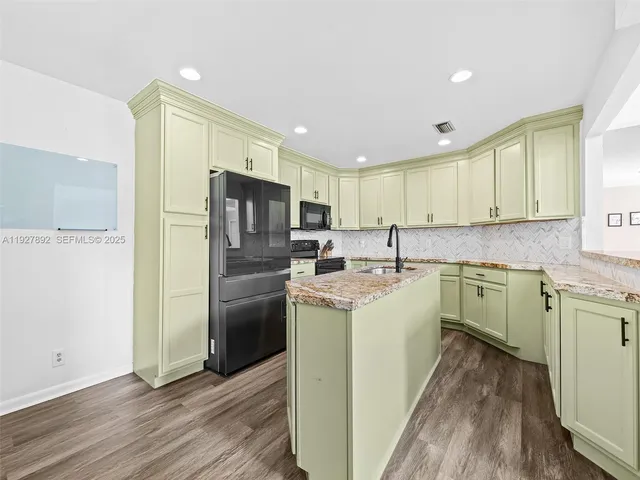 a kitchen with a sink a refrigerator a microwave oven cabinets and wooden floor