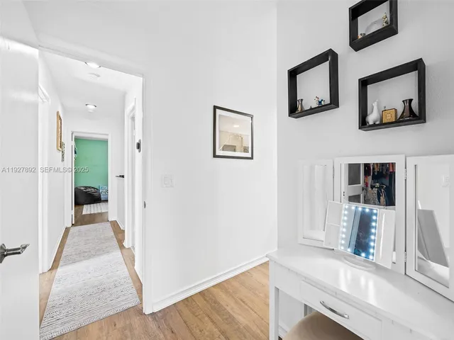 a view of a hallway with wooden floor and a flat screen tv
