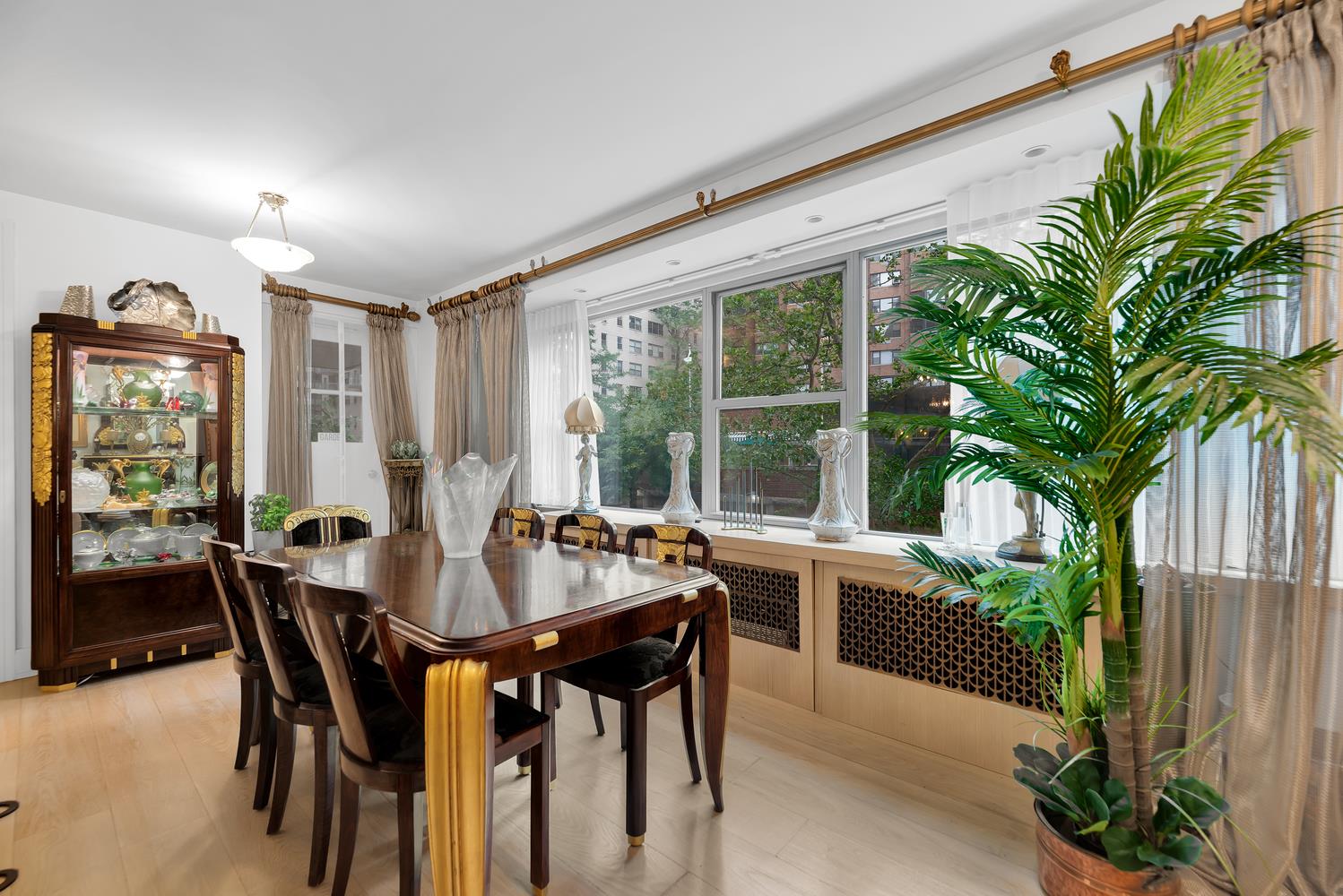 420 East 55th Street, Unit 3FG Manhattan, NY 10022 - Photo 3 of 8 a dining room with furniture potted plants and wooden floor
