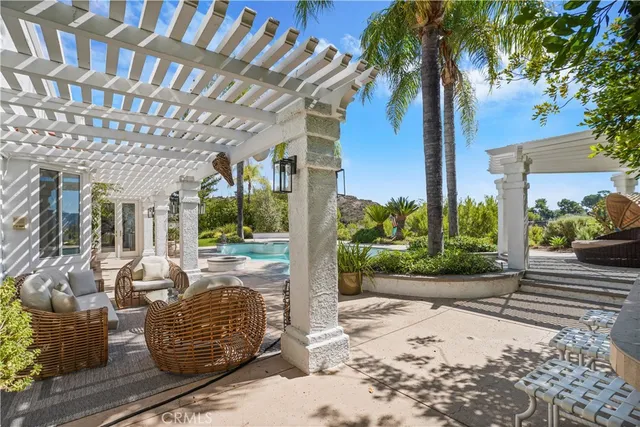 a view of a patio with couches and table and chairs under an umbrella with a large tree