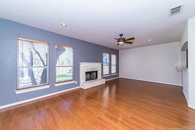 an empty room with windows and fireplace