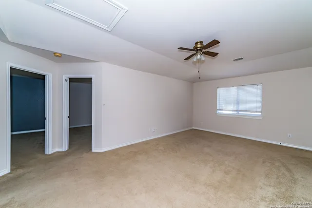 an empty room with windows and fan