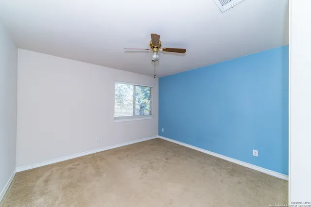 an empty room with windows and fan