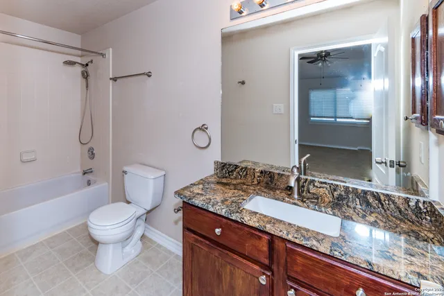 a bathroom with a granite countertop sink toilet mirror and shower