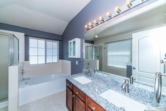 a bathroom with a granite countertop bathtub a double vanity sink and mirror