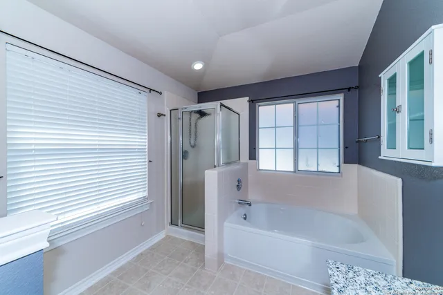 a bathroom with a bathtub a shower and a window