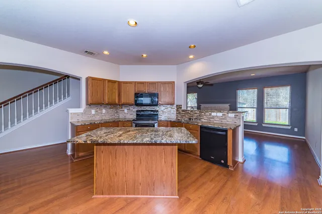a kitchen with stainless steel appliances granite countertop a sink stove and wooden floor