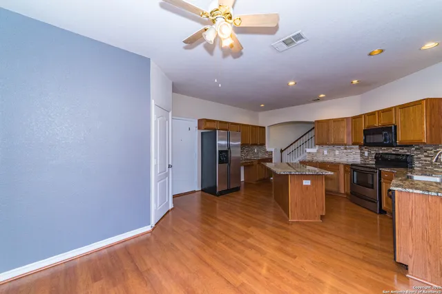 a kitchen with stainless steel appliances granite countertop a refrigerator a stove top oven a sink with island and chairs