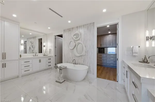 a spacious bathroom with a double vanity sink a large mirror and a bathtub