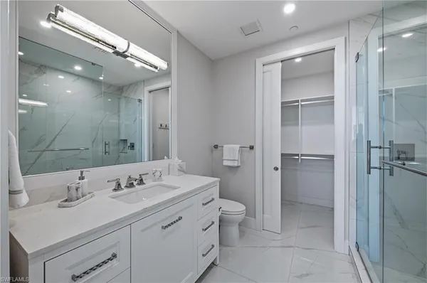 a bathroom with a double vanity sink toilet mirror and windows