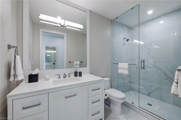 a bathroom with a toilet a sink a glass door a shower a mirror and vanity