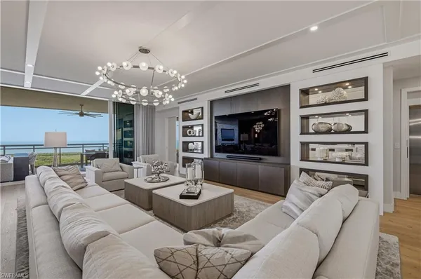 a living room with furniture a flat screen tv and a chandelier