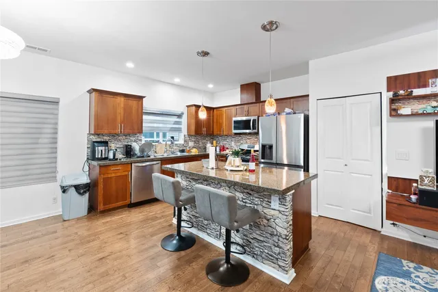a kitchen with stainless steel appliances granite countertop a refrigerator a stove and a sink