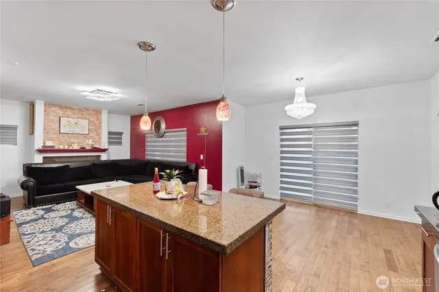 a kitchen with stainless steel appliances kitchen island granite countertop a sink cabinets and wooden floor