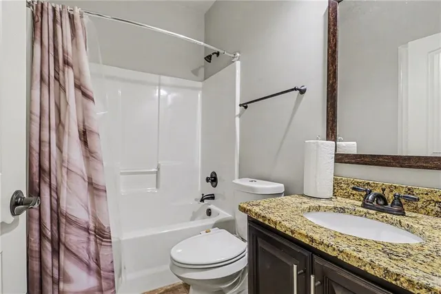 a bathroom with a granite countertop sink toilet and shower