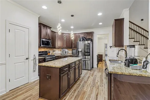 a kitchen with stainless steel appliances granite countertop a sink stove and refrigerator