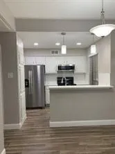 a large kitchen with stainless steel appliances a refrigerator and a wooden floor