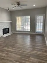 an empty room with wooden floor fireplace and windows