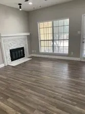 an empty room with wooden floor fireplace and windows
