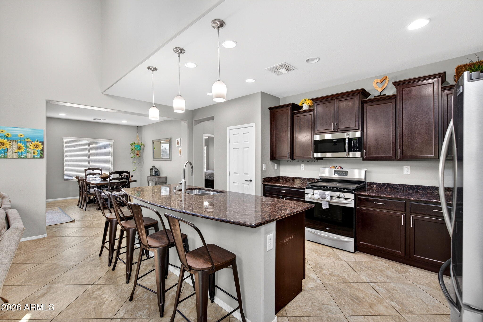 10840 West Saddlehorn Road Peoria, AZ 85383 - Photo 11 of 55 a kitchen with stainless steel appliances granite countertop wooden cabinets a refrigerator a stove a sink a dining table and chairs