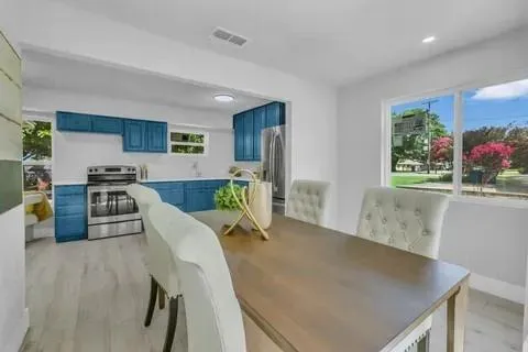 a kitchen with stainless steel appliances granite countertop a stove a refrigerator a sink a dining table and chairs with wooden floor