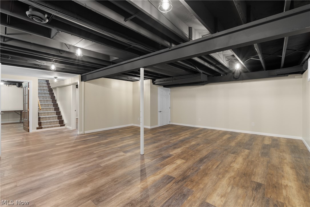 1075 Northeast River Road Lake Milton, OH 44429 - Photo 24 of 34 Spacious finished basement with wood-finish flooring, exposed black ceiling joists, and neutral wall tones