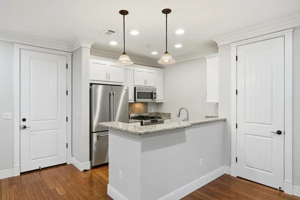 a kitchen with kitchen island a sink stainless steel appliances and wooden floor