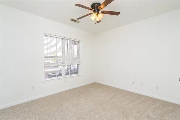 an empty room with a window and a fan