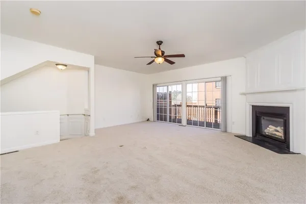 an empty room with chandelier fan and windows