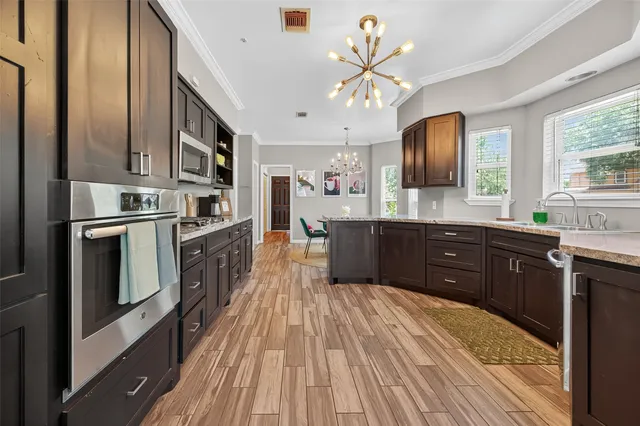 a large kitchen with stainless steel appliances granite countertop a lot of counter space and wooden floors
