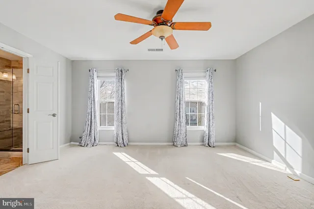 an empty room with windows and fan