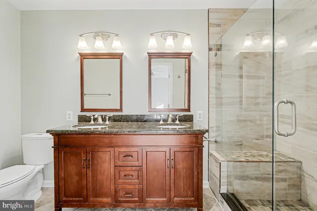 a bathroom with a granite countertop sink a toilet and a mirror