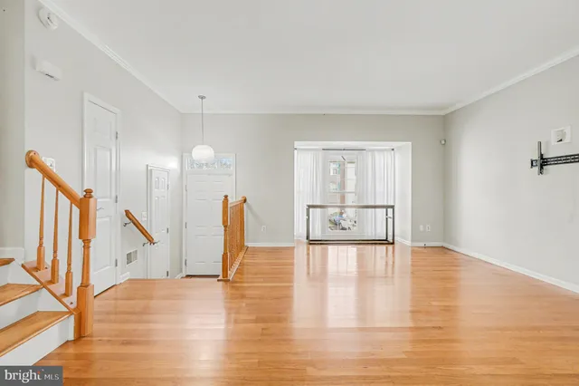 a view of an empty room with wooden floor and staircase