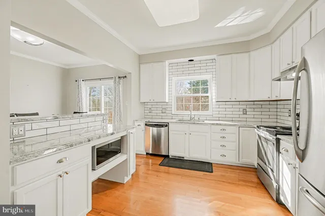 a kitchen with granite countertop white cabinets sink and stainless steel appliances