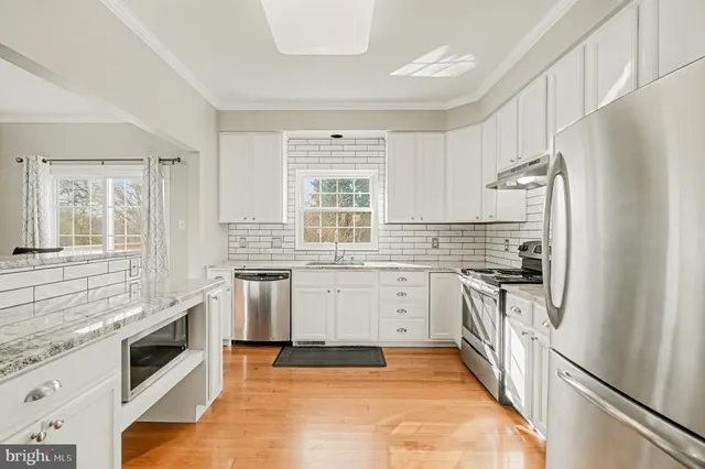 a kitchen with granite countertop a stove sink and refrigerator