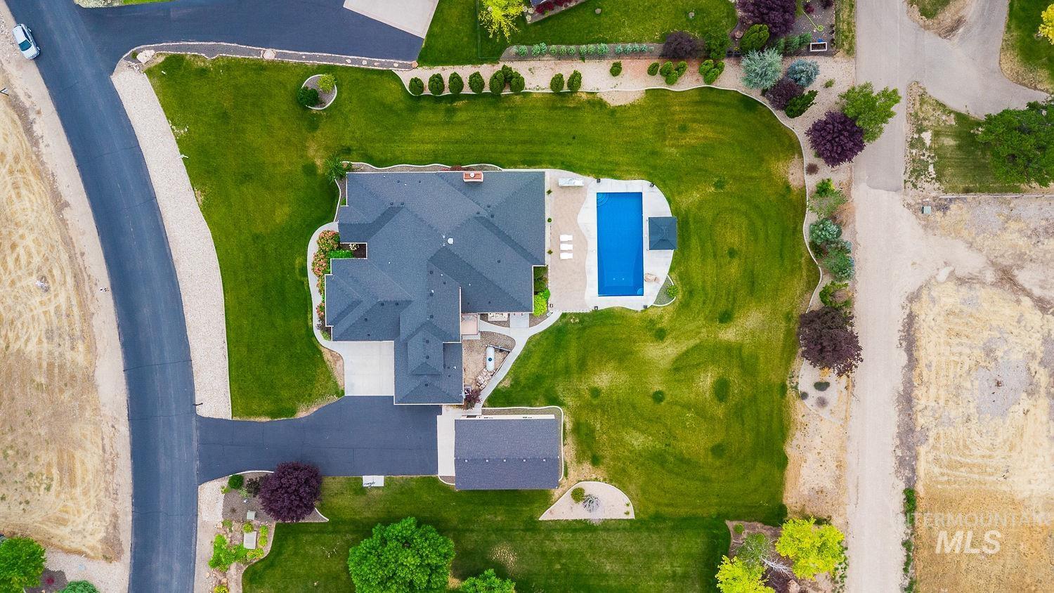 8077 Star Pass Ridge Road Nampa, ID 83686 - Photo 9 of 37 Expansive property featuring a dark-toned roofline, a large inground swimming pool with surrounding patio, and a separate detached garage structure
