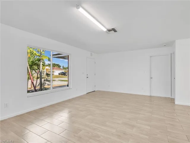 a view of an empty room with window and wooden floor