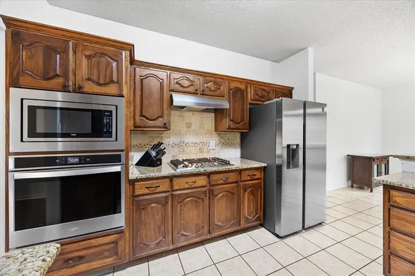 a kitchen with stainless steel appliances granite countertop a stove microwave and refrigerator