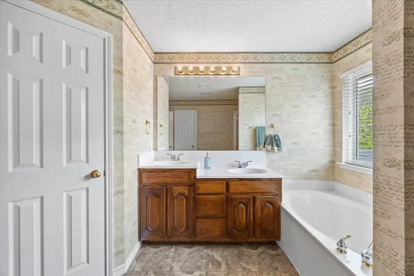 a bathroom with a granite countertop sink a mirror a bathtub and shower