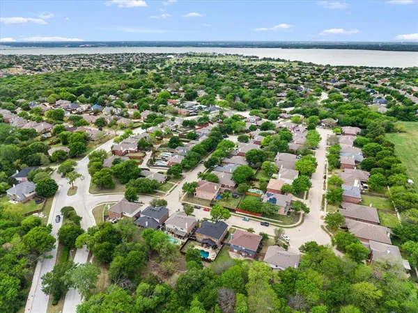 an aerial view of residential houses with outdoor space and trees all around