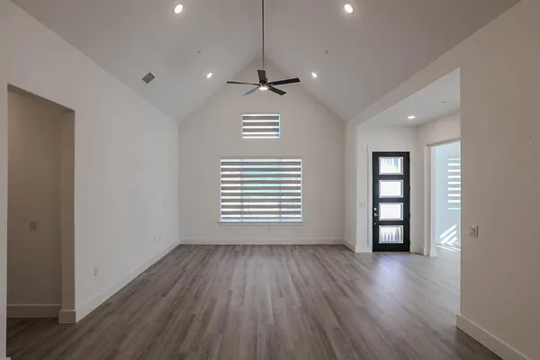 a view of an empty room with wooden floor and a window