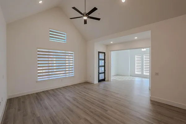 a view of an empty room with a window and wooden floor