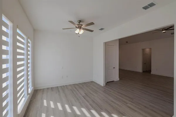 a view of empty room with wooden floor and fan