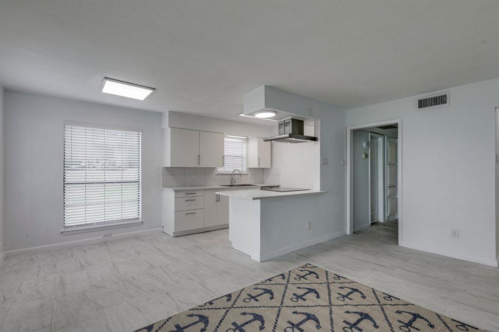 4606 Chaha Road, Unit 106 Garland, TX 75043 - Photo 14 of 22 Kitchen with sink, tasteful backsplash, black electric stovetop, white cabinets, and kitchen peninsula