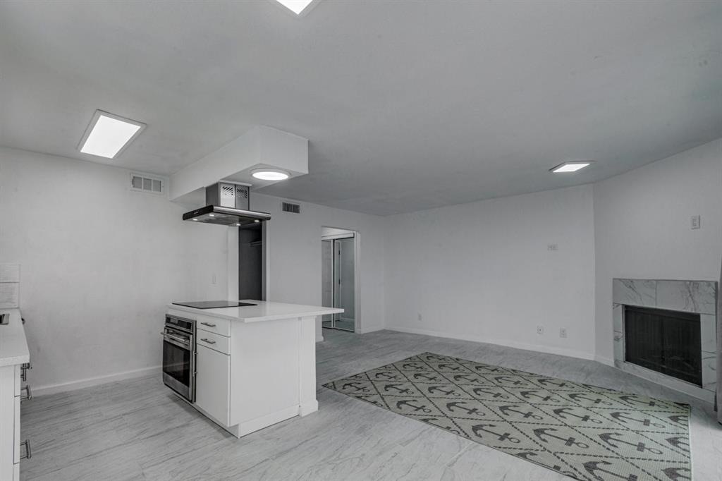 4606 Chaha Road, Unit 106 Garland, TX 75043 - Photo 2 of 22 Kitchen featuring extractor fan, white cabinets, stainless steel oven, a high end fireplace, and black electric cooktop