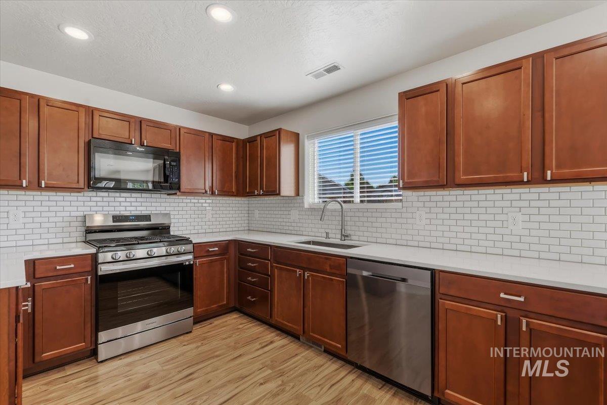 12310 West Hidden Point Drive Star, ID 83669 - Photo 8 of 48 Kitchen featuring wood-finish flooring, wood cabinetry with silver hardware, white subway tile backsplash, white countertops, and recessed lighting