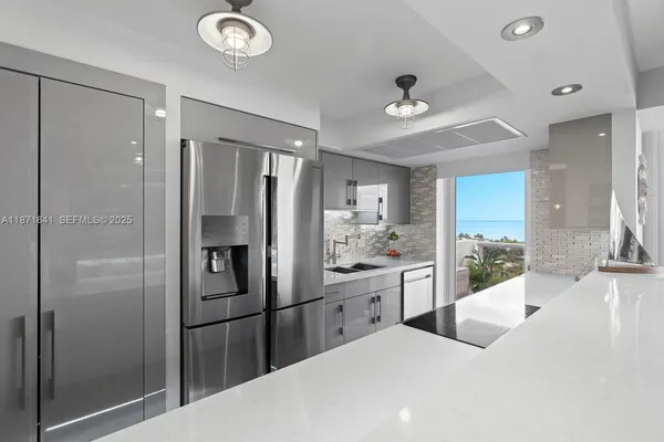 a kitchen with stainless steel appliances kitchen island granite countertop a refrigerator and a sink