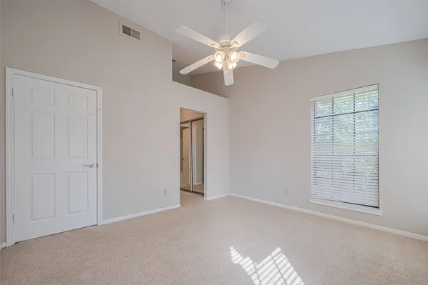 an empty room with windows and fan